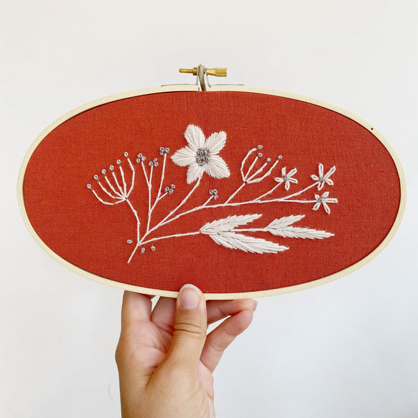 Floral embroidery stitched on dark red fabric