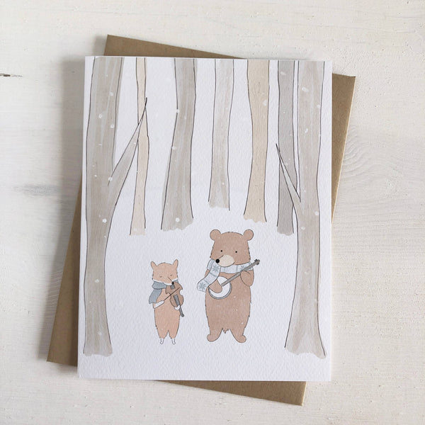Fox & Bear stand together in a forest holding instruments as the snow falls around them.